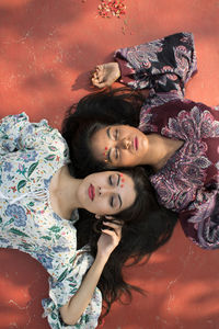 High angle view of friends lying on floor during sunny day