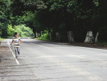 Man running on road against trees