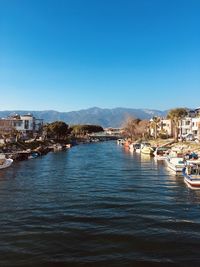 Sailboats in sea by townscape against clear blue sky