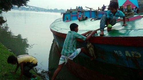 People fishing in lake against sky