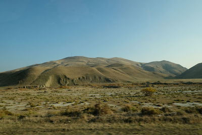 Scenic view of arid landscape against clear blue sky