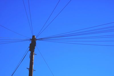 Low angle view of power lines against blue sky