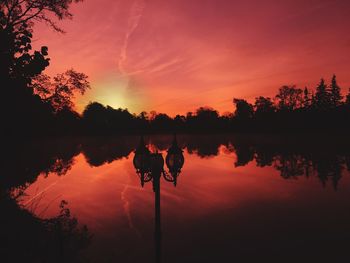 Silhouette trees by lake against sky during sunset