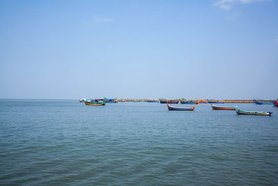 Fishing boats in sea against clear sky