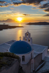 High angle view of sea by building against sky during sunset