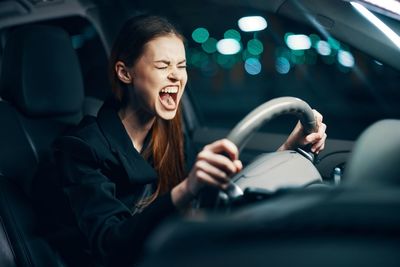 Young woman screaming while sitting in car