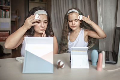 Mother and daughter applying make up at home