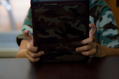 Midsection of child using digital tablet at table
