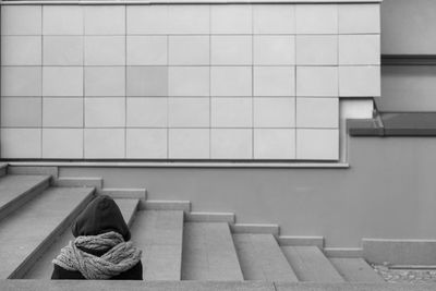 Person sitting on steps against wall