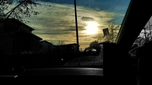 Silhouette buildings against sky seen through glass window