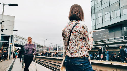 Rear view of women standing on bridge in city