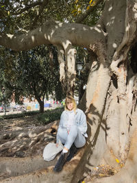 Portrait of woman sitting on tree trunk