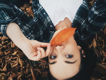 Close-up of young woman with orange leaf