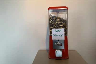 Close-up of bullets in gumball machine on table against wall