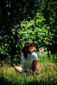 Full length of woman sitting on grassy field in park