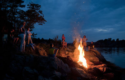 People on beach with bonfire against sky