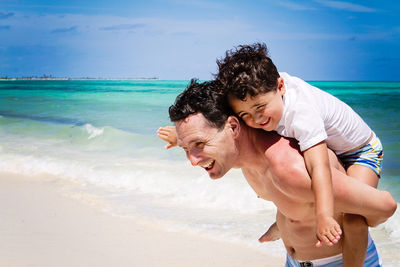 Father and son playing airplane at a beach in the caribbean.