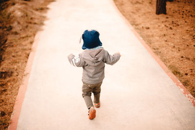 Rear view of baby boy running on footpath in park