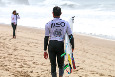 Rear view of men walking on beach