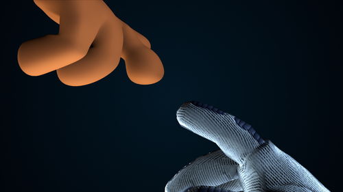 Close-up of hand against sky over black background