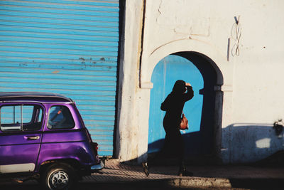 Side view of man standing by building