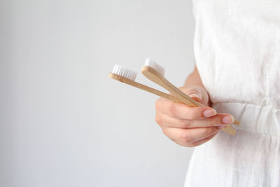 Midsection of woman writing in book against white background