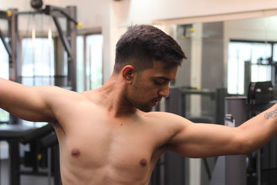 Shirtless young man flexing muscles in gym