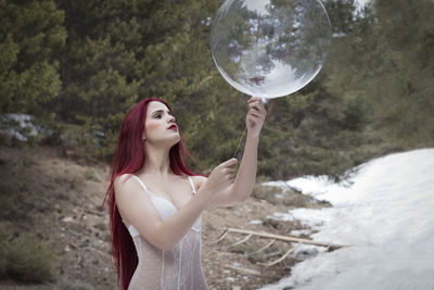 Woman with balloon standing on snowy field