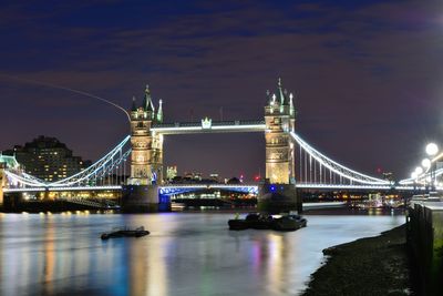 Illuminated tower bridge over thames river against sky at night