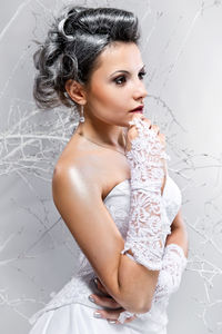 Thoughtful bride looking away while posing against white background