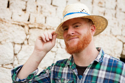 Portrait of man wearing hat against wall