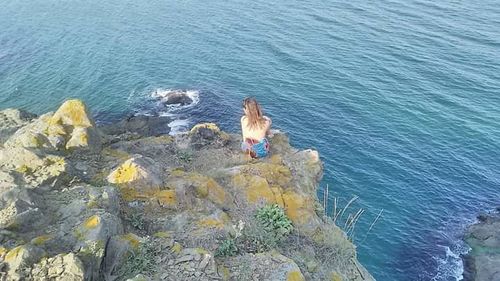 High angle view of woman on rocks by sea