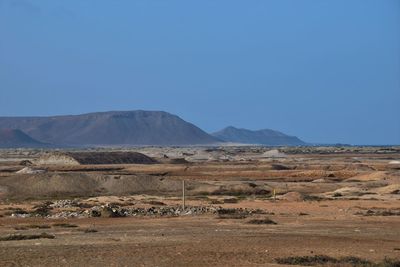 Scenic view of arid landscape against clear blue sky