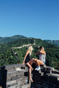 Young couple on mountain against clear blue sky