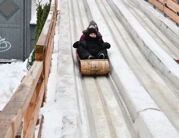 People tobogganing on snowy footbridge