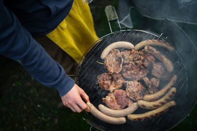 Midsection of man cooking meat on barbecue