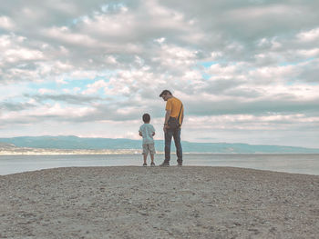Men standing on beach against sky