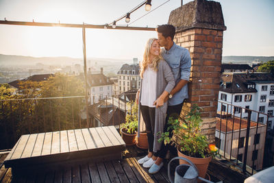 Couple standing at building terrace against sky