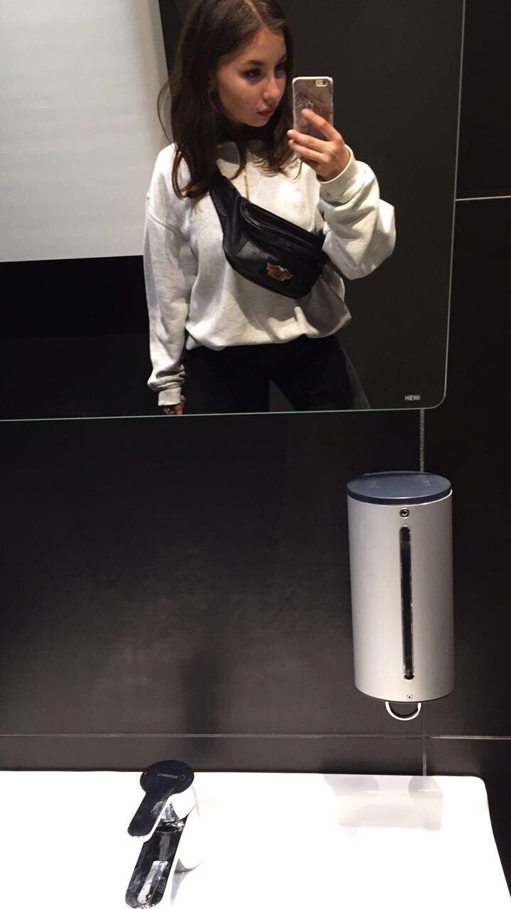 YOUNG WOMAN USING SMART PHONE IN MIRROR