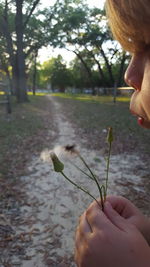 Girl blowing dandelion seed at park