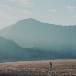 Man standing on arid landscape against sky