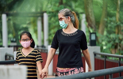 The mother and daughter walking together in a public park during the covid-19 pandemic