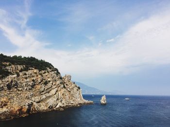 Scenic view of sea and cliff against sky