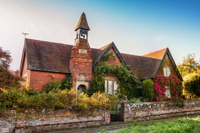 Old building by trees against sky