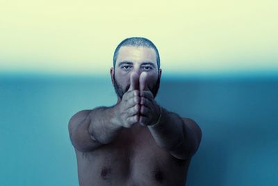 Portrait of shirtless man in sea against sky