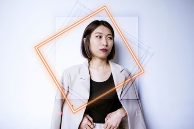 Portrait of young woman standing against white background