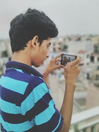 Teenage boy photographing while standing at terrace