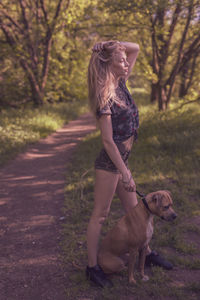 Full length of woman standing with dog on field at park