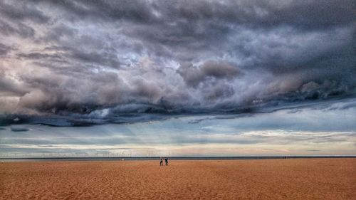 Scenic view of beach against cloudy sky