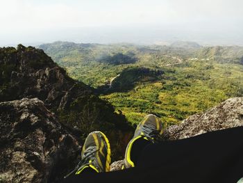 Low section of woman standing on mountain against sky